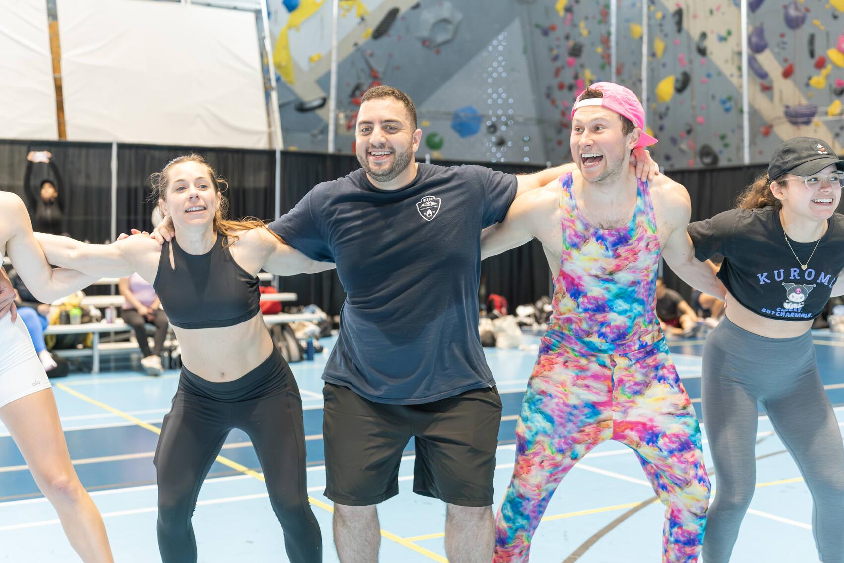 Smiling friends linking arms during an indoor climbing event